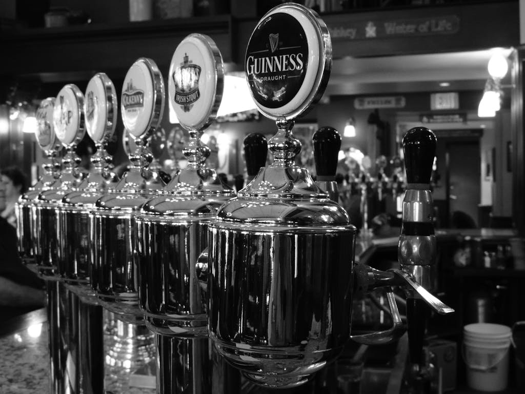 Monochrome image of beer taps in a bar with a focus on the Guinness logo.